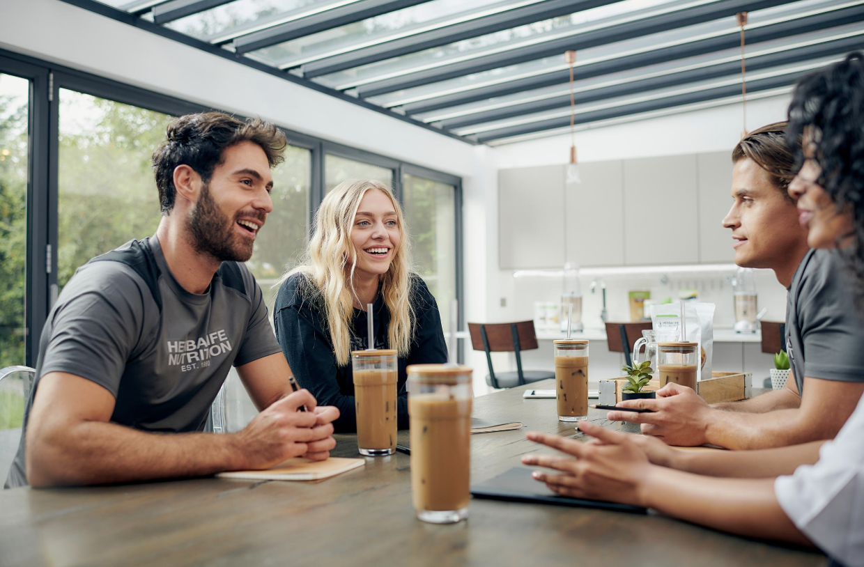 Vier Personen bei einem entspannten Gespräch mit Kaffee - SINA Marketing GmbH Team